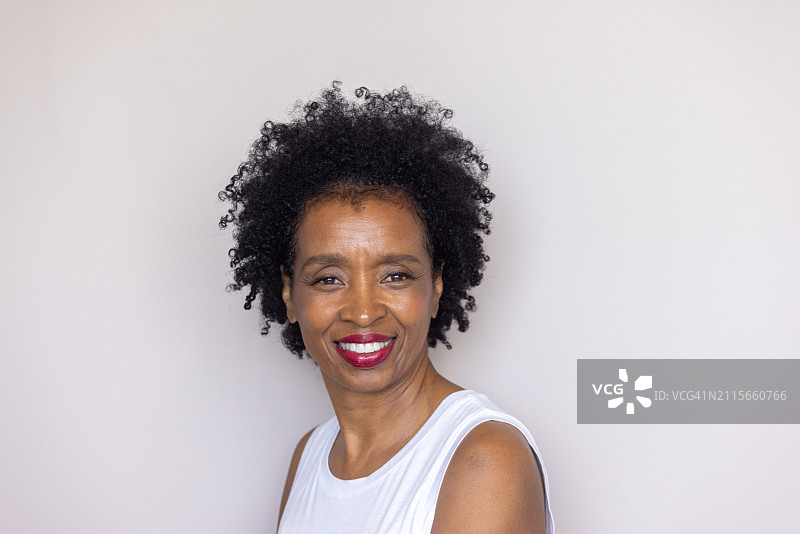 卷发、淡妆、身穿白色无袖上衣的年长非裔美国女人肖像图片素材