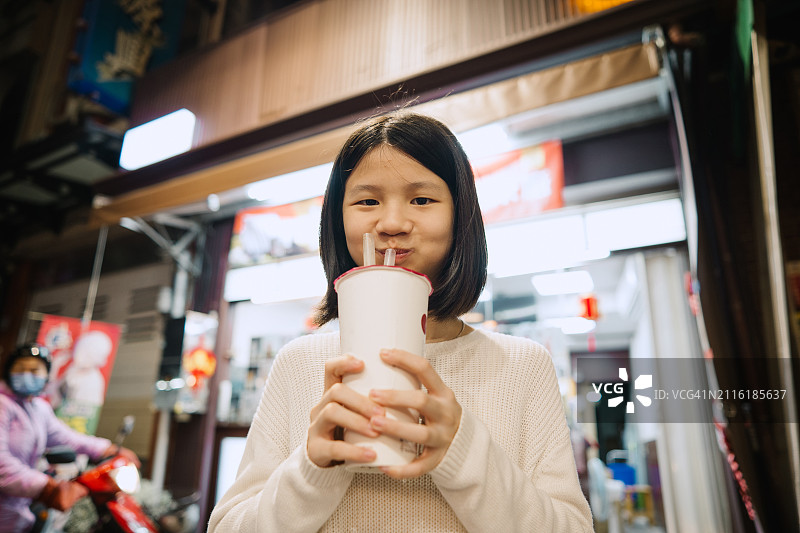 年轻的亚洲儿童在户外喝一杯饮料图片素材