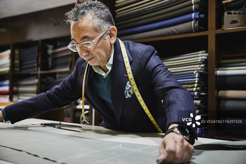 工作室里，裁缝在桌子上铺开裁剪好的西装面料图片素材