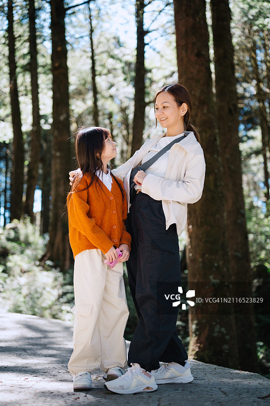 幸福的一家：母亲和可爱的女儿在森林里享受亲情图片素材
