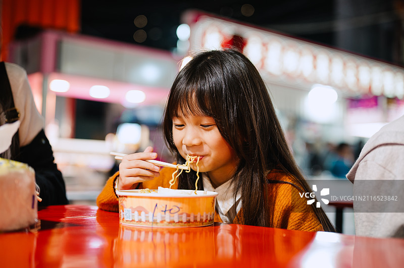 华人儿童享受夜市街头美食图片素材