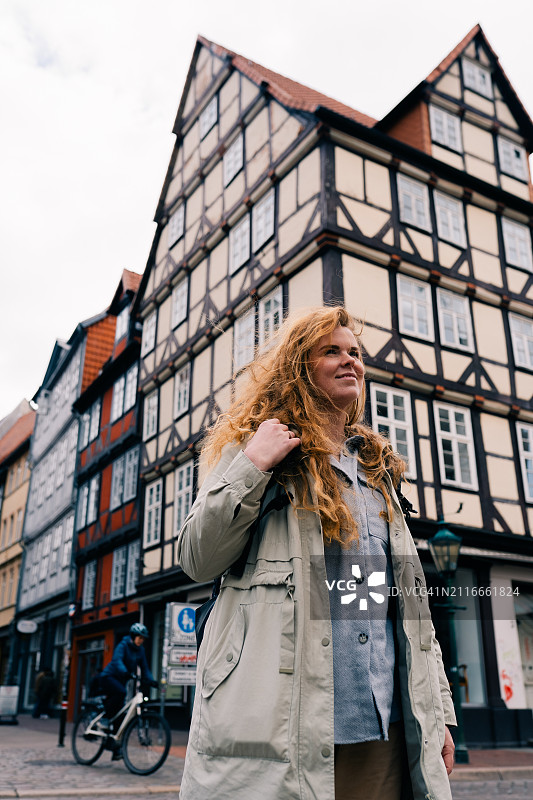年轻女人走在德国下萨克森州汉诺威老城区，传统桁架房屋图片素材