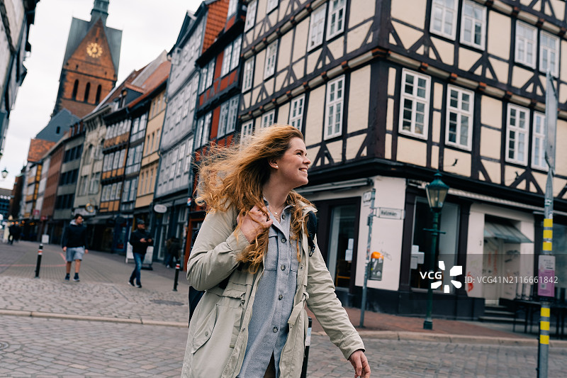 年轻女人走在德国下萨克森州汉诺威老城区，传统桁架房屋图片素材