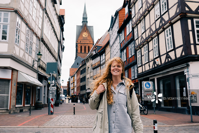 年轻女人走在德国下萨克森州汉诺威老城区，传统桁架房屋图片素材