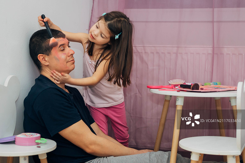 小女孩用彩妆盘给爸爸化眼影图片素材