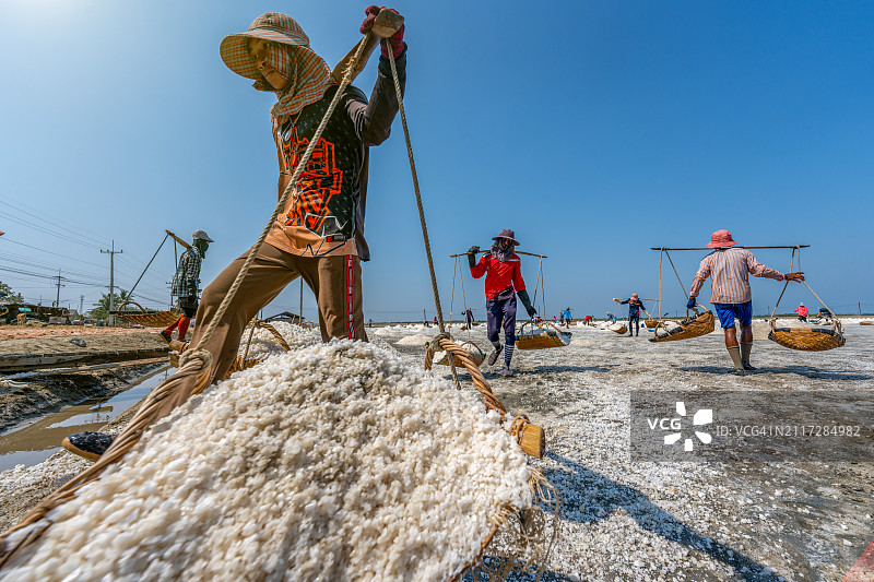 泰国沙没沙空府盐场工人运输盐的场景图片素材
