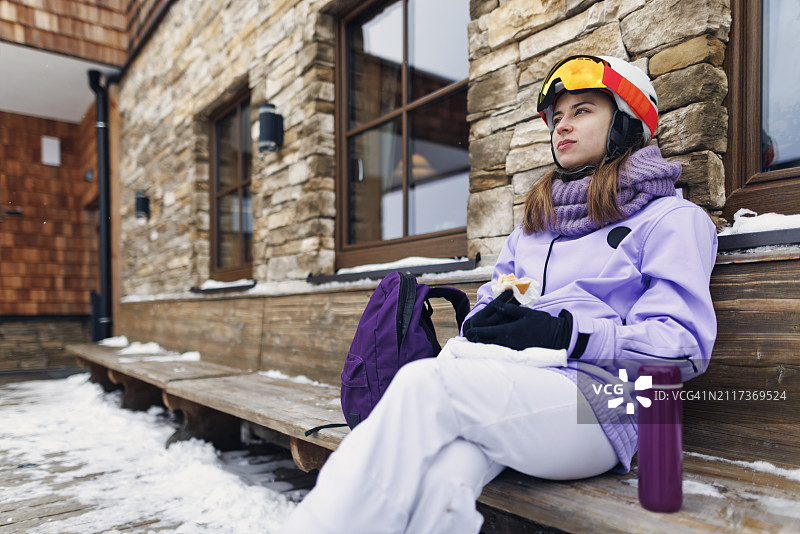 年轻女子在冬季阿尔卑斯山滑雪胜地休息图片素材