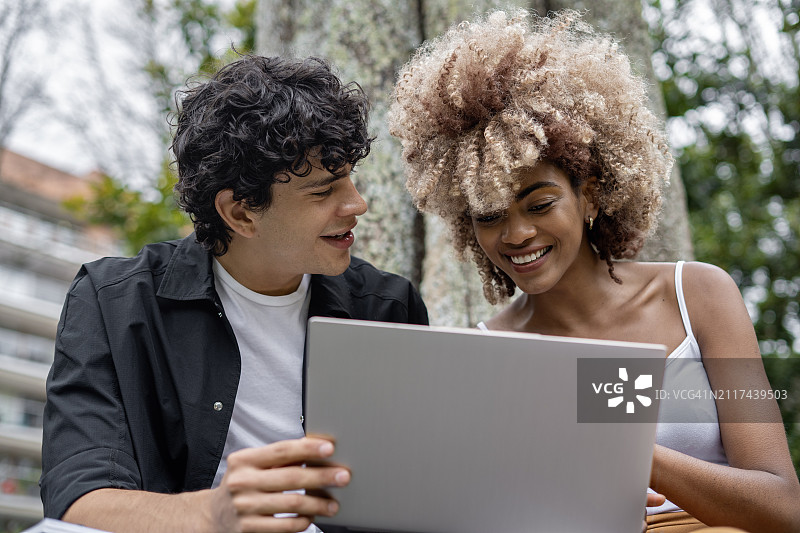 在户外公园电脑前的快乐大学生图片素材