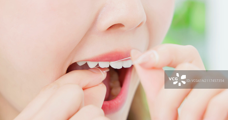 快乐的亚洲女人用牙线清洁牙齿图片素材