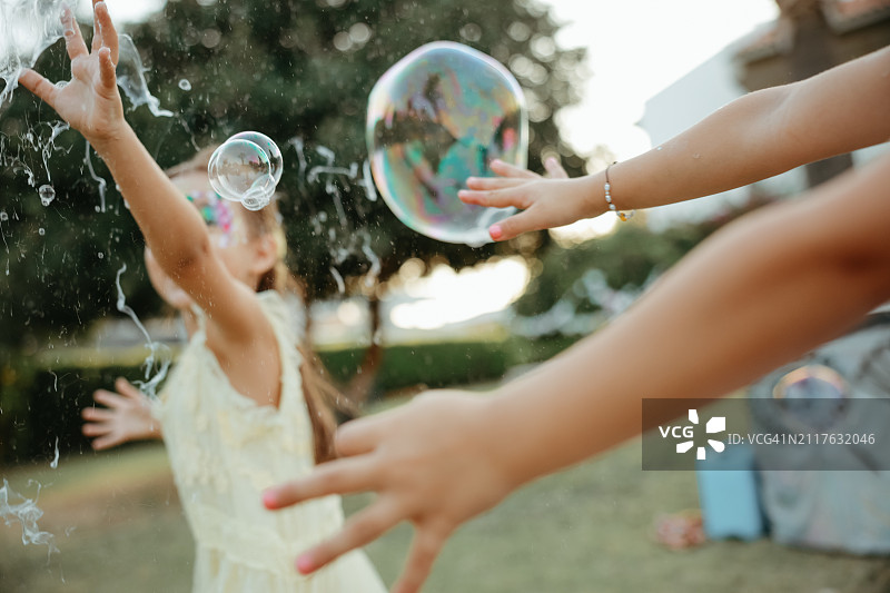 在阳光明媚的夏日泡沫派对或节日上，头上沾满泡沫、穿着湿衣服的快乐小女孩图片素材