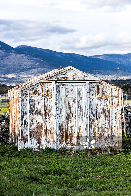 草地中央的废弃生锈铁皮棚图片素材