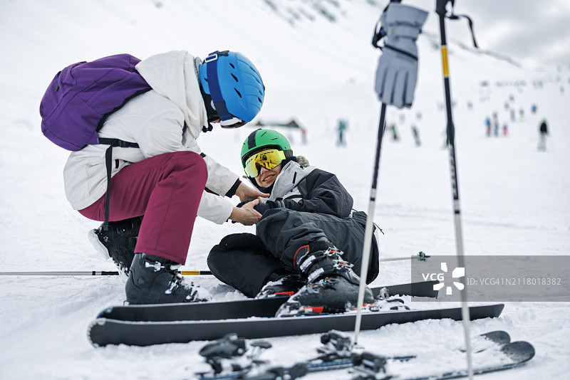 母亲查看滑雪摔倒后男孩的手图片素材