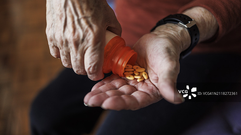 退休后服用处方药，老年妇女手中的药瓶图片素材