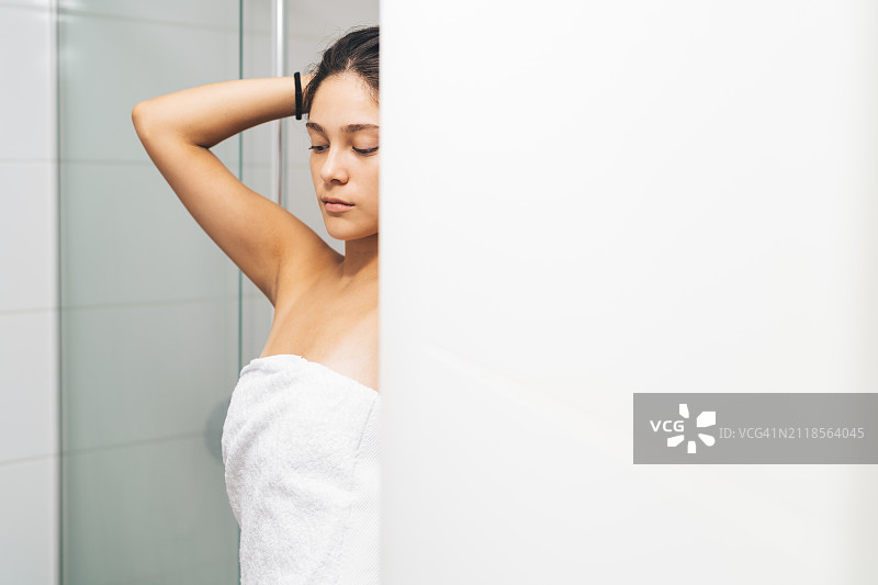 淋浴前，在镜子前整理头发的年轻女子图片素材
