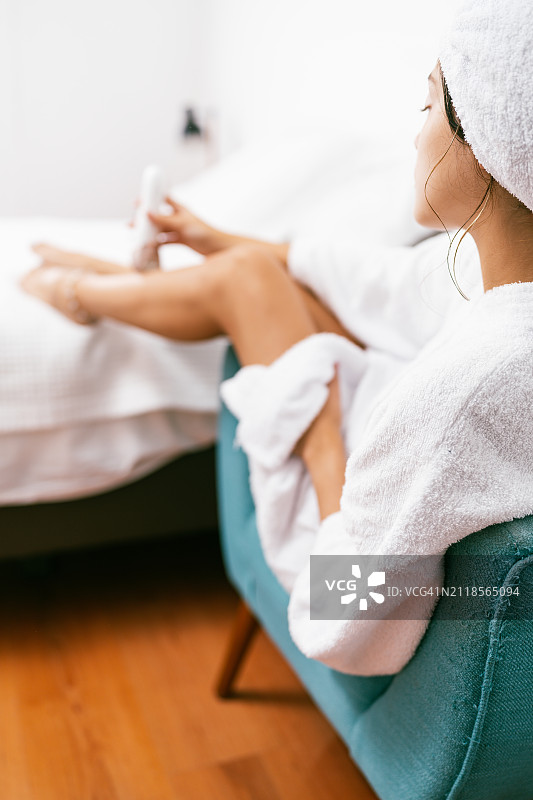 年轻女子使用脱毛机为身体脱毛图片素材