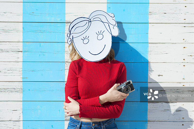 戴自制纸板面具的女人和老式相机图片素材