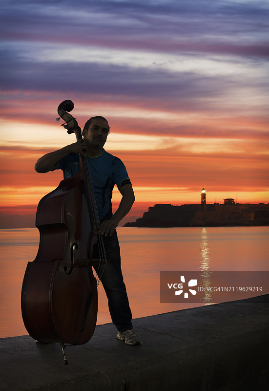 古巴哈瓦那，男人在日落时分的马雷贡演奏贝斯图片素材