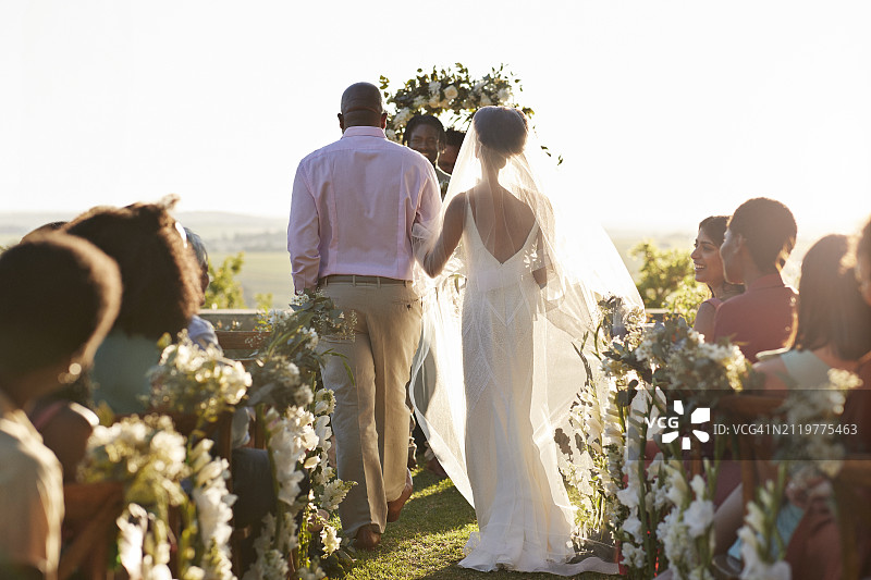 父亲和新娘在婚礼宾客的簇拥下走过通道图片素材
