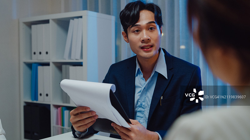 在办公室与商务女士交谈的年轻亚洲商务男士图片素材