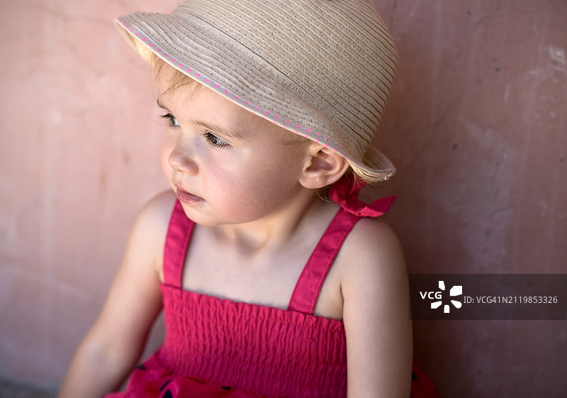 戴着帽子靠墙站立的可爱女孩图片素材