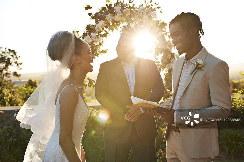 背光牧师与快乐的新娘和新郎宣读结婚誓言图片素材