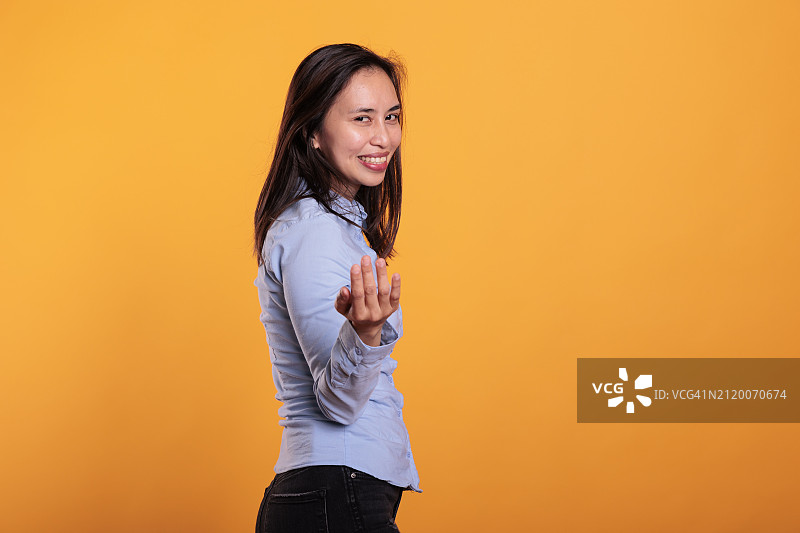 在橙色背景前的微笑年轻女人肖像图片素材