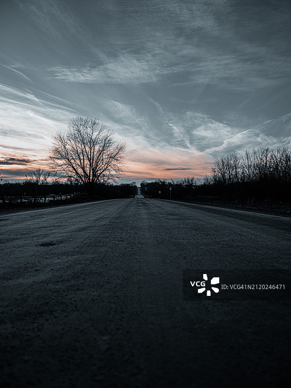 美国爱荷华州索伦：日落时分天空下的林间空旷道路图片素材