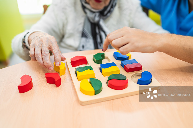 老人玩彩色积木拼图特写图片素材