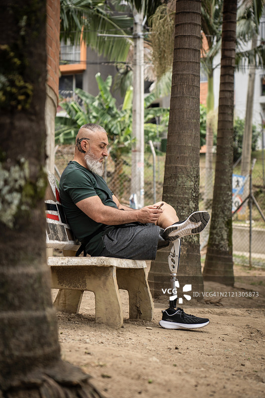 坐在户外看手机的残疾男子全身照图片素材