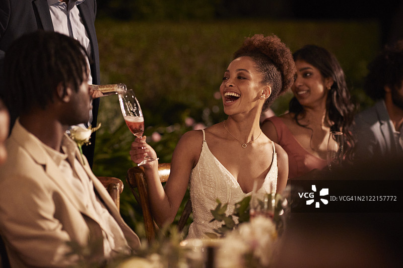 男子为与新郎和客人坐在一起的新娘倒饮料图片素材