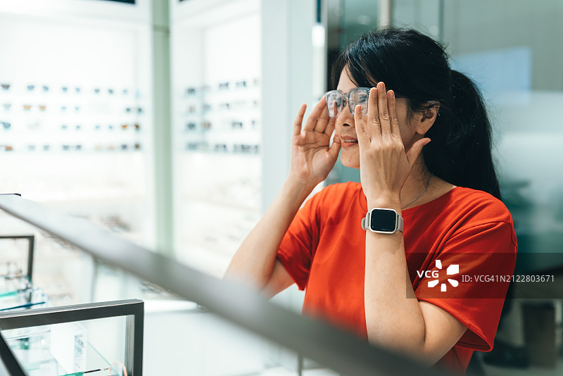 女人在眼镜店购买并试戴眼镜——视力概念图片素材