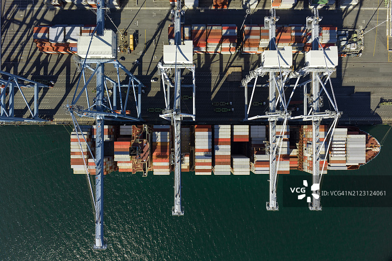 集装箱起重机悬在货船上方的无人机俯视照片图片素材