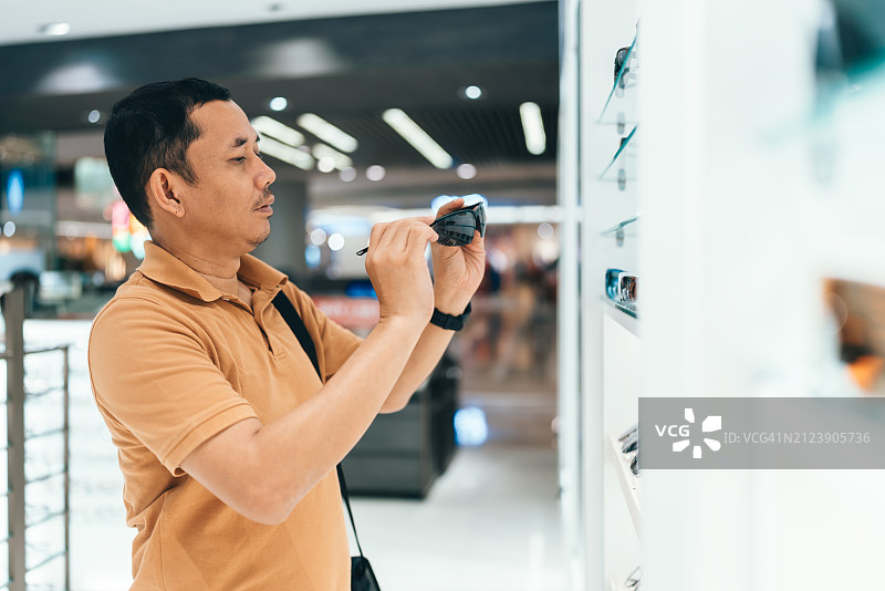 男人在眼镜店购买眼镜并试戴——视力概念图片素材