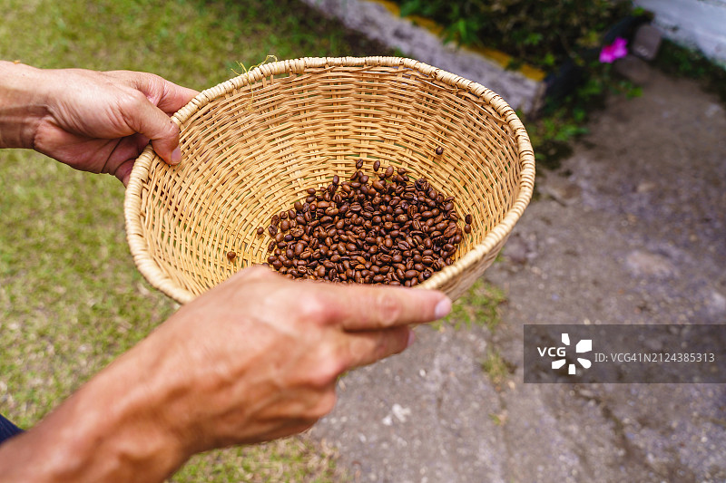 男农民用柳条筐晒咖啡豆的特写图片素材