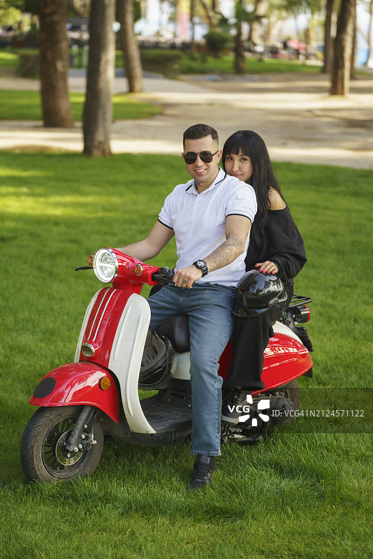 可爱的年轻夫妇在公园骑摩托车图片素材