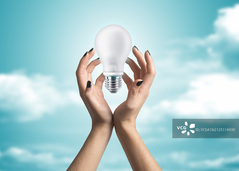女人的手拿着一个白色的灯泡图片素材