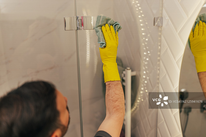 用抹布擦拭淋浴玻璃的手部特写图片素材