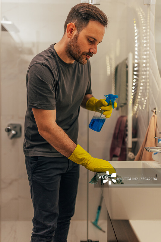 男人用喷雾瓶清洁浴室水槽图片素材