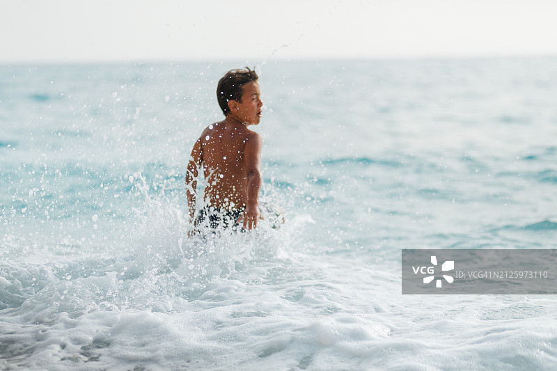 男孩在海浪中嬉戏，玩得很开心图片素材
