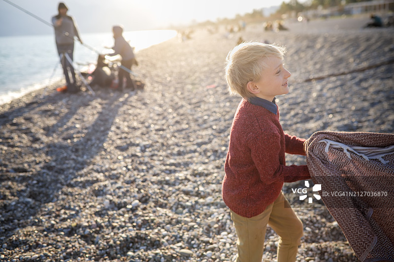 甜蜜的兄妹情：孩子们在海边穿着毛衣在石头海滩上嬉戏图片素材