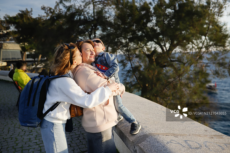 海边的家庭爱：母亲、祖母和儿子在土耳其海滨长廊上温柔地拥抱图片素材