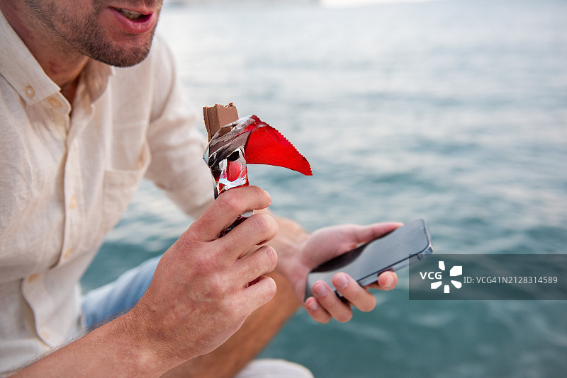 红胎记男子海边吃巧克力特写图片素材