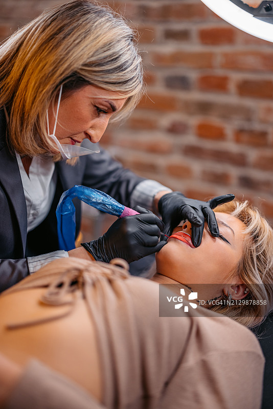 女美容师在美容院为顾客纹唇图片素材