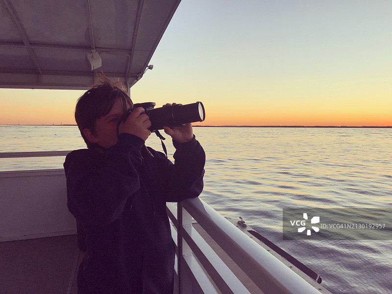 日落时分，小男孩在钦科蒂格岛乘船游览，正在拍照。周末度假。图片素材