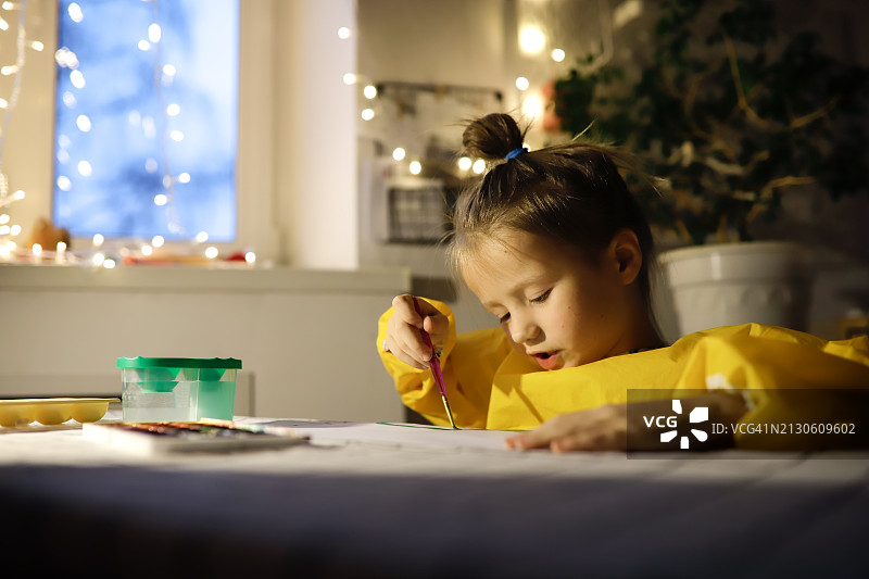 儿童艺术家在柔和灯光下创作水彩杰作，在舒适的家中探索想象力图片素材