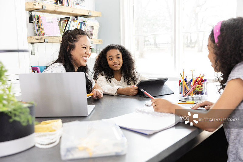 妈妈和年轻女孩在学习时，因青少年的笑话而开怀大笑图片素材
