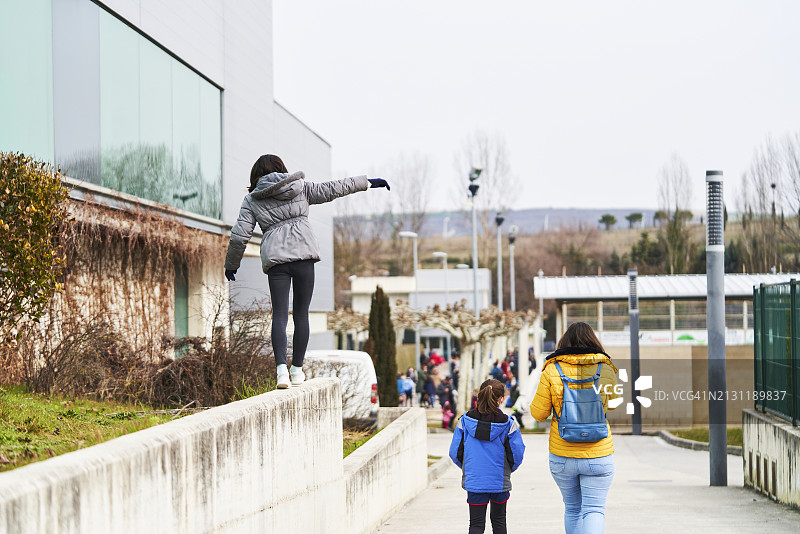 一位女士和她的三个女儿在公园里散步的背影图片素材