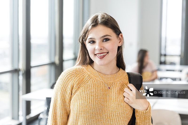 少女在离开教室前停下来对着镜头微笑图片素材