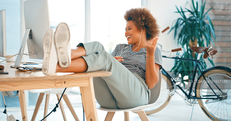 商务女人在办公室放松和使用桌面电脑，连接和听音乐以激发创造力。设计师唱歌并使用耳机在时尚机构中进行音频流传输技术，用于在线研究图片素材