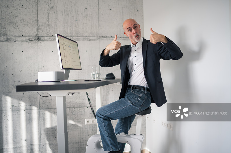 男人在家用办公室享受可调节高度的桌子和自行车图片素材